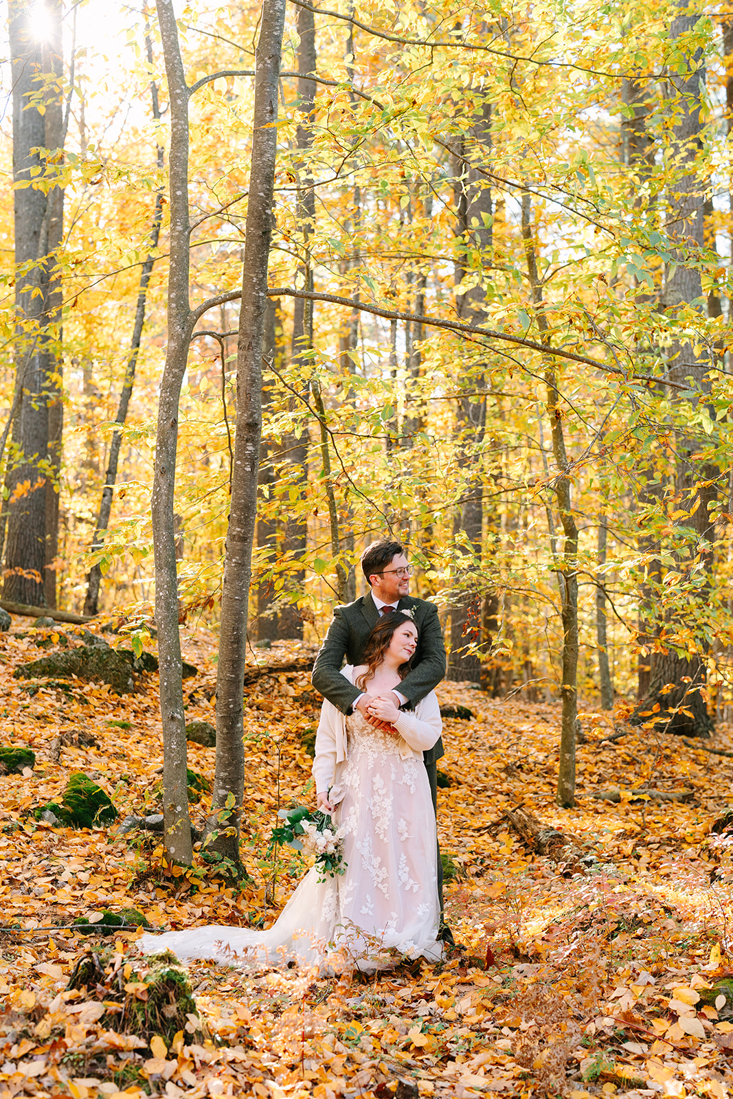 A couple hugs in the woods at a stunning Maine elopement location.