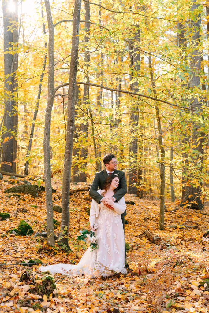 A couple stand in a forest during Fall in one of the best places to elope in Maine.