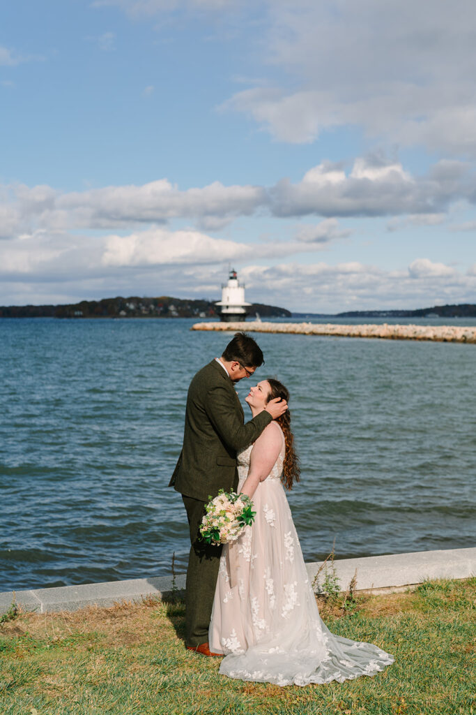 A couple stands in front of a Maine lighthouse in Portland, one of Maine's best places to elope.